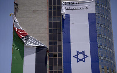 إزالة علم فلسطيني عن مبنى من قبل السلطات الإسرائيلية بعد أن رفعته مجموعة مناصرة للتعايش بين الفلسطينيين والإسرائيليين، في رمات غان، 1 يونيو، 2022. (AP Photo / Oded Balilty)