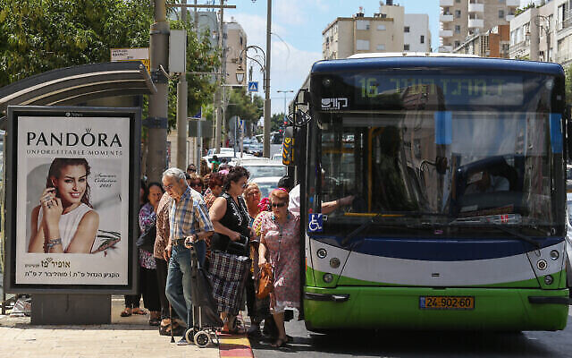 إسرائيليون يستقلون حافلة "كافيم" في الشارع الرئيسي في وسط مدينة بتاح تكفا، 24 يونيو، 2015 (Nati Shohat / FLASH90)