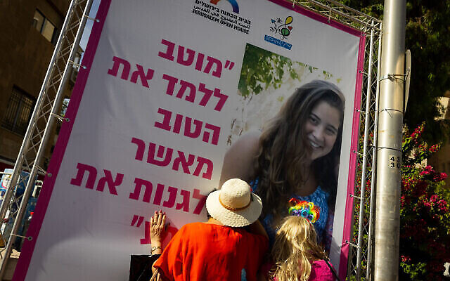 أشخاص في مسيرة الفخر المثلية في القدس، 3 يونيو 2021، ينظرون إلى صورة شيرا بانكي، التي قُتلت على يد متطرف أرثوذكسي متشدد في مسيرة عام 2015 (Olivier Fitoussi / Flash90)