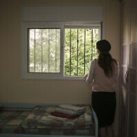 توضيحية: امرأة تنظر من نافذة غرفتها في ملجأ للنساء المعنفات، 15 يوليو 2014 (Hadas Parush / Flash90)