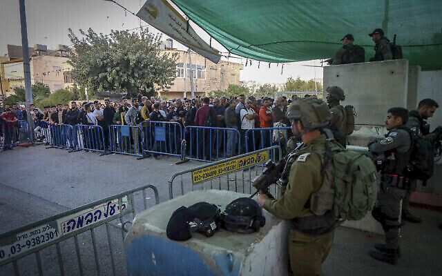 جنود إسرائيليون يقفون في حراسة، بينما يشق الفلسطينيون طريقهم عبر نقطة تفتيش لحضور صلاة الجمعة في المسجد الأقصى بالقدس، بالقرب من مدينة بيت لحم بالضفة الغربية، 29 أبريل، 2022 (Wisam Hashlamoun / Flash90 / File)