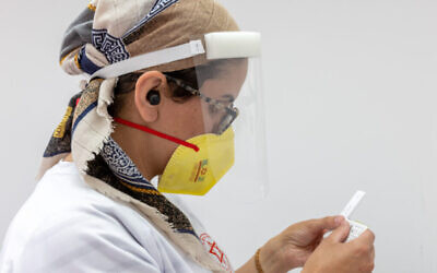 عاملة رعاية صحية تعالج عينات مسحة من إسرائيليين في مركز اختبار كورونا، 28 يونيو 2022 (Yossi Aloni / Flash90)