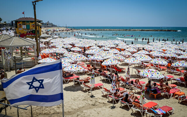 إسرائيليون يستجمون بالشاطئ في تل أبيب في يوم حار، 9 يوليو 2022 (Avshalom Sassoni / Flash90)