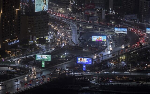 مركبات تسير من أمام اللوحات الإعلانية المضاءة على طول شارع "6 أكتوبر" الذي يمر عبر وسط العاصمة المصرية القاهرة، 24 أغسطس 2022 (Khaled DESOUKI/AFP)