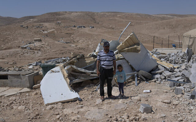 محمد أبو صبحة (46 عاما) وابنته زينب في صورة وسط أنقاض منزل عائلته الذي هدمه الجيش الإسرائيلي، في قرية الفخيت الفلسطينية في مسافر يطا، الضفة الغربية، 1 أغسطس، 2022. (AP/Nasser Nasser)