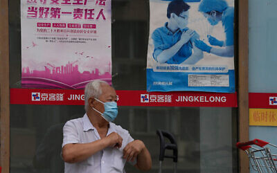 توضيحية: رجل يقف بالقرب من ملصق يروج للتطعيم في بكين، الصين، 19 يوليو، 2022. (AP Photo / Ng Han Guan)