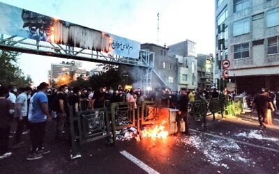 صورة حصلت عليها وكالة فرانس برس خارج إيران في 21 سبتمبر 2022، تظهر متظاهرين إيرانيين يحرقون حاوية قمامة في العاصمة طهران خلال احتجاج على وفاة محسة أميني في حجز "شرطة الأخلاق" (AFP)
