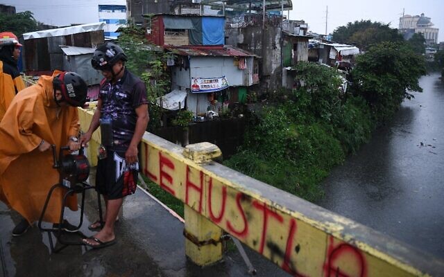 مسؤولون يستخدمون صفارات الإنذار لتحذير السكان من الاقتراب من جدول في ضواحي مدينة كويزون في ضواحي مانيلا، 25 سبتمبر، 2022، مع وصول الإعصار نورو إلى الفلبين . . ( Ted ALJIBE / AFP)