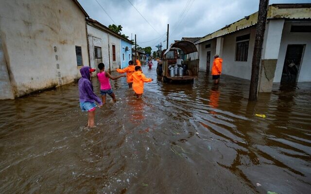 أشخاص يسيرون في شارع غمرته المياه في باتابانو ، كوبا ، في 27 سبتمبر 2022 ، أثناء مرور إعصار إيان. (YAMIL LAGE / AFP)