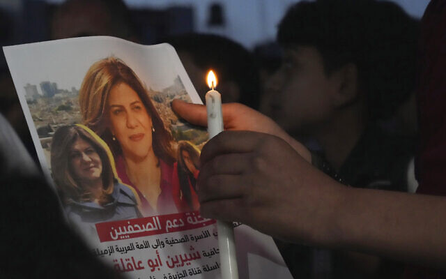 فلسطيني يحمل شمعة وصورة صحفية الجزيرة المقتولة شيرين أبو عاقلة، أمام مكتب شبكة الجزيرة في مدينة غزة، 11 مايو 2022 (AP Photo/Adel Hana, File)
