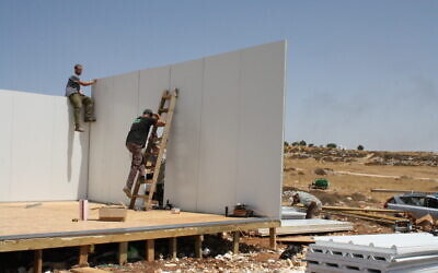 نشطاء المستوطنين يعيدون بناء أحد المباني في بؤرة "رمات ميغرون" الاستيطانية غير القانونية في الضفة الغربية، 16 أغسطس 2022 (Jeremy Sharon/Times of Israel)