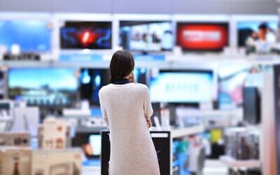 امرأة تنظر إلى أجهزة التلفزيون في المتجر (Filipovic018 at iStock, Getty Images)