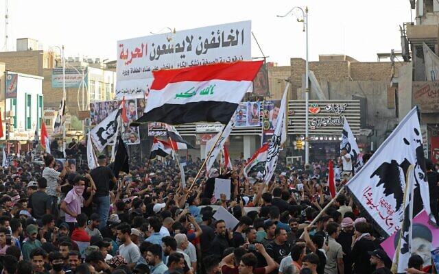 متظاهرون عراقيون يرفعون لافتات وأعلام وطنية خلال مسيرة لإحياء ذكرى مرور ثلاث سنوات على اندلاع المظاهرات في جميع أنحاء البلاد ضد الفساد المستشري، في ساحة الحبوبي في مدينة الناصرية الجنوبية، 1 أكتوبر 2022 (Asaad NIAZI / AFP)