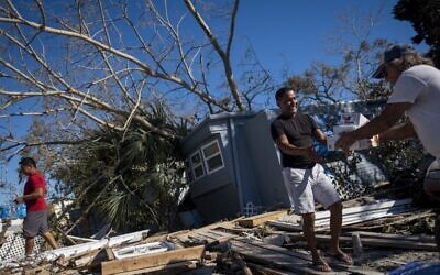 خوسيه راميريز يتلقى  الطعام والإمدادات من أحد جيرانه في أعقاب إعصار إيان في فورت مايرز بيتش ، فلوريدا في 2 أكتوبر، 2022.  ( Ricardo ARDUENGO / AFP)