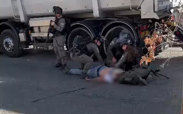 عناصر من شرطة حرس الحدود يعالجون فايز دمدوم (18 عامًا)، الذي أصيب برصاص القوات بعد محاولته إلقاء زجاجة حارقة، 1 أكتوبر 2022. (Screenshot: Twitter)