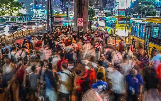 أشخاص ينتظرون وصول الحافلات إلى محطة في ماندالويونغ، مترو مانيلا، في 14 أكتوبر 2022 - وفقًا للأمم المتحدة، سيتجاوز عدد سكان العالم 8 مليار في 15 نوفمبر (JAM STA ROSA / AFP)