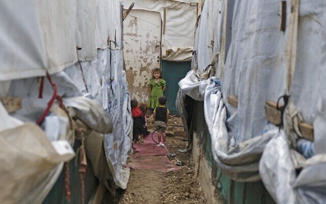 توضيحية: أطفال يقفون بين خيام في مخيم مؤقت للاجئين السوريين في تل حياة، قضاء عكار شمال لبنان، 26 أكتوبر 2022 (Ibrahim Chalhoub / AFP)