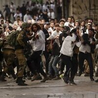قوات الأمن الإسرائيلية تستخدم وسائل لتفريق أعمال الشغب وسط اشتباكات بين إسرائيليين وفلسطينيين، خلال زيارة مصلين إسرائيليين لقبر عثنيئيل في مدينة الخليل بالضفة الغربية، 19 نوفمبر، 2022. (HAZEM BADER / AFP)