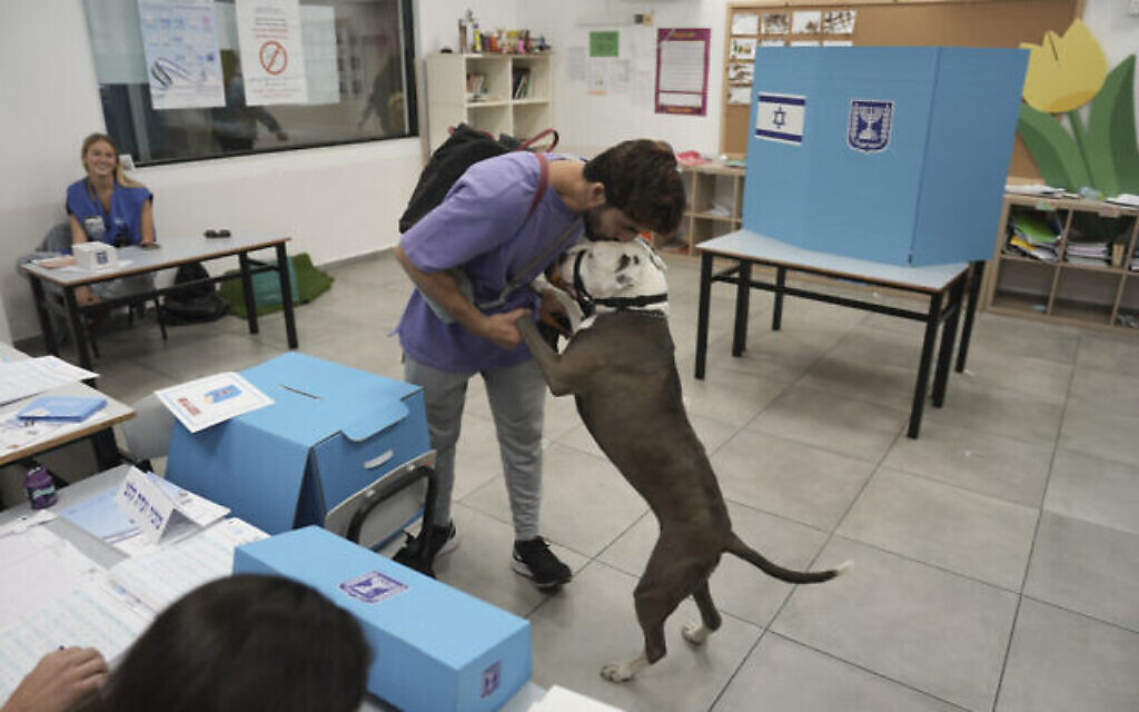 رجل يقبل كلبه بعد أن أدلى بصوته خلال الانتخابات الإسرائيلية في تل أبيب، الثلاثاء 1 نوفمبر، 2022. (AP Photo / Ariel Schalit)