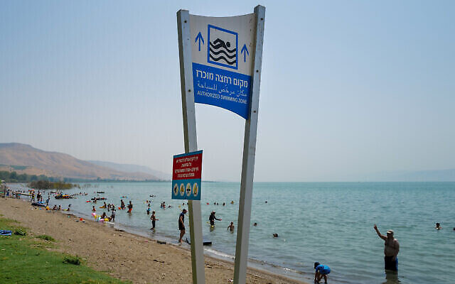 إسرائيليون يستمتعون بالأيام الأخيرة من العطلة الصيفية في يوم شديد الحرارة على شاطئ دوغا، على الضفاف الشرقية لبحيرة طبريا، 30 أغسطس، 2022. (Michael Giladi / Flash90)