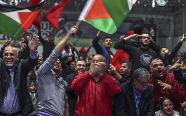 مشجعو كرة قدم فلسطينيين يرفعون الأعلام المغربية والفلسطينية ويهتفون وهم يشاهدون مباراة الجولة السادسة عشر من كأس العالم قطر 2022 بين البرتغال والمغرب، في مدينة غزة، 10 ديسمبر 2022 (MOHAMMED ABED / AFP)