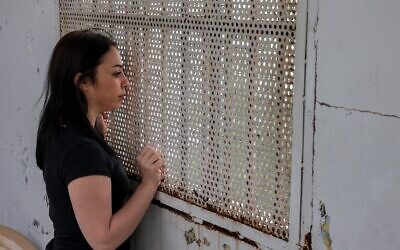 بشرى، سجينة تبلغ من العمر 28 عامًا في سجن بعبدا للنساء، والتي تم اعتقالها في وقت سابق من هذا العام بتهمة التشهير، تنظر من خلال الشبكة التي تغطي النافذة خلال مقابلة في المنشأة الواقعة شرق العاصمة اللبنانية/ 12 ديسمبر 2022 (JOSEPH EID / AFP)