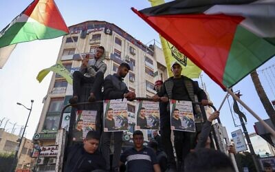 فلسطينيون يلوحون بأعلامهم الوطنية ويحملون صور ناصر أبو حميد خلال مظاهرة بعد وفاته داخل سجن إسرائيلي، في مدينة رام الله بالضفة الغربية، 20 ديسمبر 2022 (Abbas Momani / AFP)