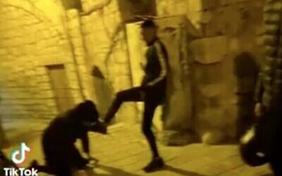 رجل حريدي ينحني ويقبل قدم فتى فلسطيني في البلدة القديمة في القدس. قُبض على قاصرين فلسطينيين في الحادثة التي وقعت في الأول من ديسمبر، 2022. (Screen capture / Twitter)