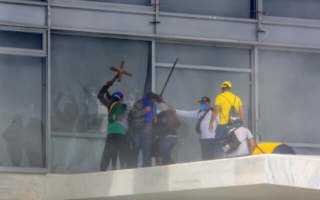 أنصار الرئيس البرازيلي السابق جاير بولسونارو يكسرون نافذة أثناء اقتحامهم لقصر بلانالتو الرئاسي في برازيليا، 8 يناير 2023 (Sergio LIMA / AFP)