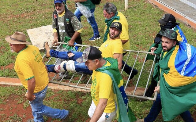 إجلاء أحد أنصار الرئيس البرازيلي السابق جاير بولسونارو بعد إصابته خلال اشتباكات مع شرطة مكافحة الشغب خارج قصر بلانالتو الرئاسي في برازيليا، 8 يناير 2023 (Sergio Lima / AFP)