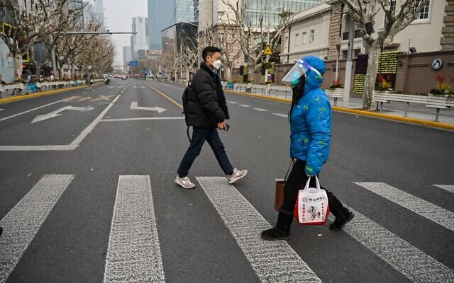 امرأة ترتدي قناعًا وسط جائحة كوفيد-19 تمشي في شارع في في شنغهاي، الصين، 9 يناير 2023 (Hector Retamal / AFP)