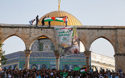 رفع العلم الفلسطيني ولافتة لحركة حماس بعد صلاة عيد الاضحى في الحرم القدسي، 20 يوليو، 2021. (Jamal Awad / Flash90)