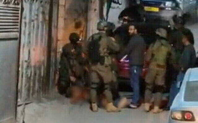 جنود إسرائيليون يحيطون بجثة سمير أصلان (41 عاما)  في مخيم قلنديا بالقرب من القدس، 12 يناير، 2023. (Screenshot: Twitter)