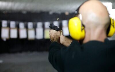 رجل يطلق النار من مسدس في ميدان رماية داخلي خلال دورة تأهيلية في كاتسرين في الجولان، 31 يناير، 2023. (JALAA MAREY / AFP)