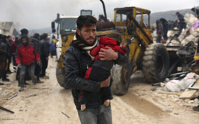 رجل يحمل جثة أحد ضحايا زلزال قرية بسنية قرب الحدود التركية بمحافظة إدلب السورية، 6 فبراير، 2023. (AP Photo / Ghaith Alsayed)