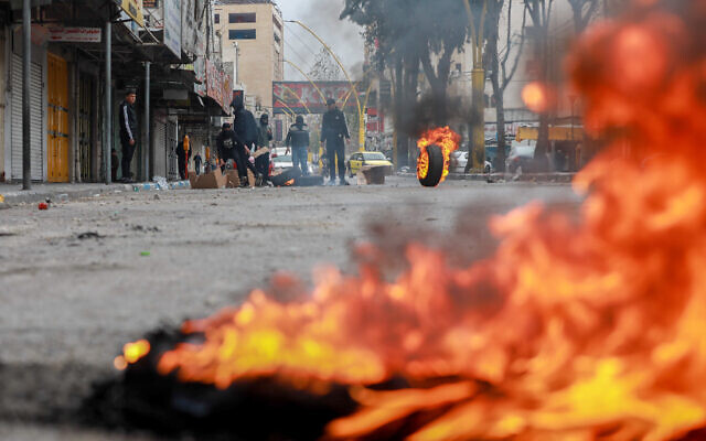 فلسطينيون يحرقون الإطارات خلال مواجهات مع القوات الإسرائيلية في مدينة الخليل بالضفة الغربية، 23 فبراير 2023 (Wisam Hashlamoun / Flash90)