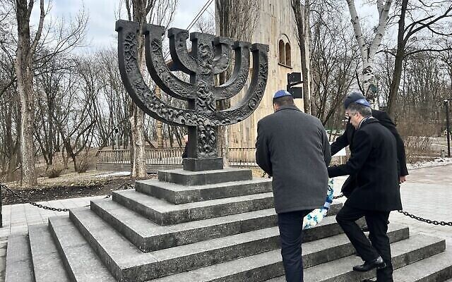 وزير الخارجية إيلي كوهين (يمين) يضع إكليلا من الزهور في وادي بابين يار، حيث قتل النازيون والمتعاونون معهم أكثر من 30 ألف يهودي في سبتمبر 1941، في كييف، أوكرانيا، 16 فبراير، 2023. (Lazar Berman / Times of Israel)