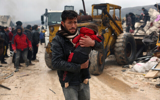 رجل يحمل أحد ضحايا الزلزال في قرية بسنية قرب الحدود التركية بمحافظة إدلب، سوريا، 6 فبراير 2023 (AP Photo / Ghaith Alsayed)