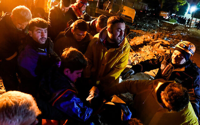 عمال الإنقاذ يحملون جثة شخص انتشلت من تحت أنقاض مبنى مدمر في أضنة، تركيا، 6 فبراير 2023 (AP Photo / Khalil Hamra)