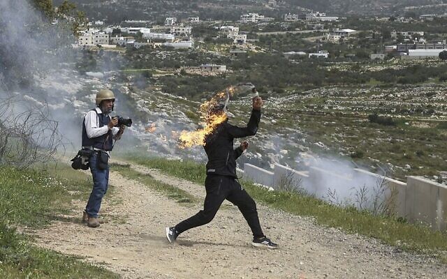 توضيحية: فلسطيني يلقي زجاجة حارقة وسط مواجهات مع قوات الأمن الإسرائيلية، خلال مظاهرة بمناسبة يوم الأرض في قرية بلعين في الضفة الغربية، 1 أبريل 2022 (Abbas Momani / AFP)