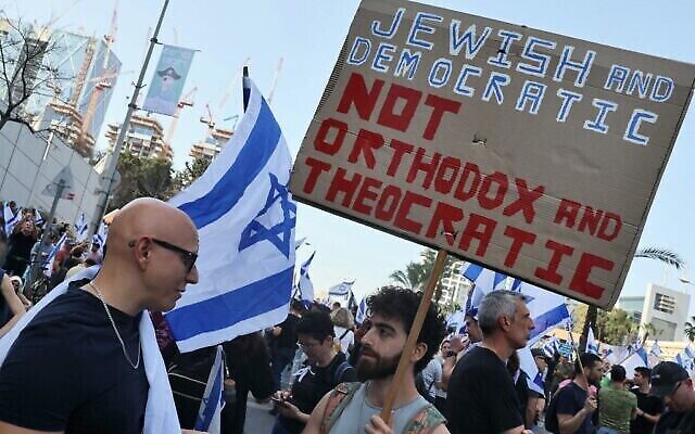 متظاهرون يحملون لافتات خلال مظاهرة ضد مشروع قانون الحكومة المثير للجدل لإصلاح النظام القضائي في تل أبيب، 1 مارس، 2023. (JACK GUEZ / AFP)