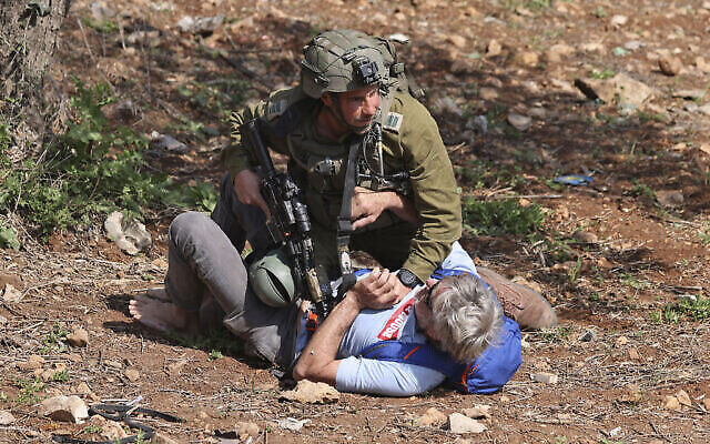 جندي يشتبك مع متظاهر أثناء تظاهرة نشطاء سلام فلسطينيين وإسرائيليين عند مدخل حوارة في الضفة الغربية، 3 مارس، 2023. (Jaafar ASHTIYEH / AFP)