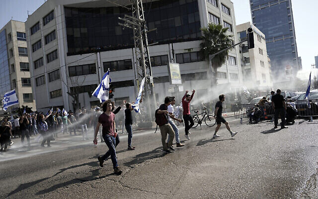 الشرطة تنشر خراطيم المياه لتفريق المتظاهرين الذين أغلقوا طريقا رئيسيا احتجاجا على خطط الحكومة لإصلاح النظام القضائي، في تل أبيب، إسرائيل، 1 مارس، 2023. (Oded Balilty / AP)