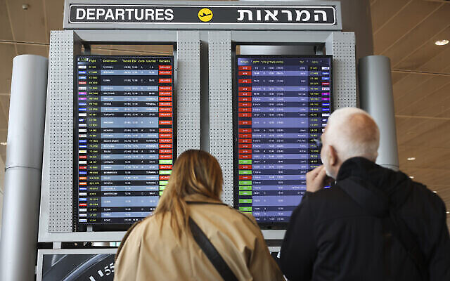 مسافرون ينظرون إلى الشاشة التي تعرض الرحلات المتأخرة في مطار بن غوريون، 27 مارس، 2023. (AP Photo / Oren Ziv)