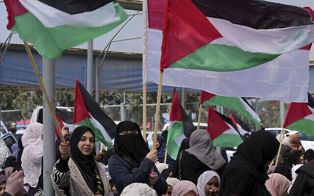 نساء فلسطينيات يلوحن بالأعلام خلال مسيرة لإحياء الذكرى الـ47 ليوم الأرض، على طول السياج الحدودي مع إسرائيل، شرقي مدينة غزة، 30 مارس، 2023. (AP / Adel Hana)