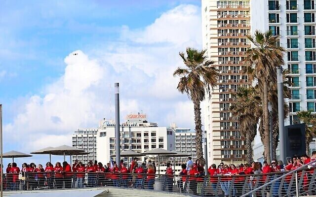 مئات النساء اللواتي يرتدين الزي الأحمر بمناسبة اليوم العالمي للمرأة ويتظاهرن ضد الإصلاح القضائي الذي تخطط له الحكومة، على الشاطئ في تل أبيب، 8 مارس، 2023. (Tomer Neuberg / Flash90)