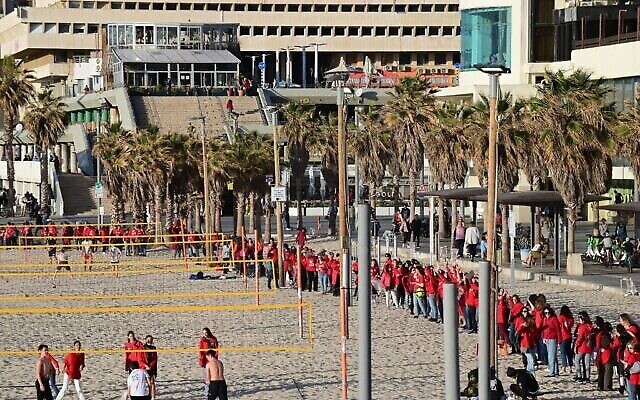 مئات النساء اللواتي يرتدين الزي الأحمر بمناسبة اليوم العالمي للمرأة ويتظاهرن ضد الإصلاح القضائي الذي تخطط له الحكومة، على الشاطئ في تل أبيب، 8 مارس، 2023. (Tomer Neuberg / Flash90)