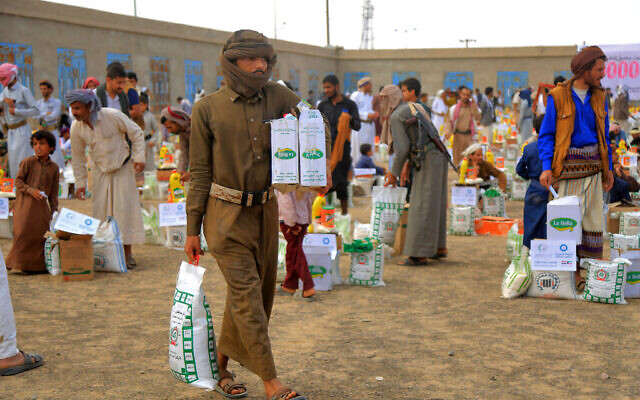 توضيحية: رجال يحملون مساعدات إنسانية قدمتها منظمة خيرية كويتية خلال عملية توزيع على النازحين اليمنيين في ضواحي مدينة مأرب الشمالية الشرقية في 6 أبريل 2023 (STR / AFP)