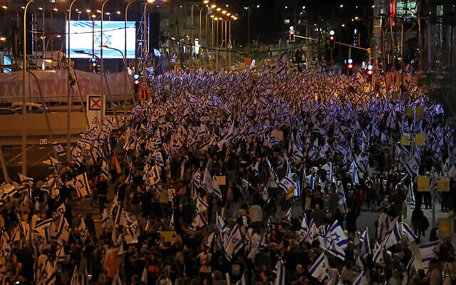 متظاهرون يرفعون الأعلام الإسرائيلية وسط مظاهرات مستمرة ضد خطط الحكومة لإصلاح النظام القضائي، في تل أبيب، 15 أبريل، 2023. (JACK GUEZ / AFP)