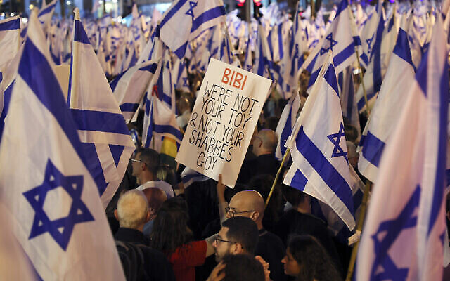 متظاهرون يرفعون الأعلام واللافتات خلال مظاهرة احتجاجية على خطط الحكومة الإسرائيلية للإصلاح القضائي، في تل أبيب، 22 أبريل، 2023. (JACK GUEZ / AFP)